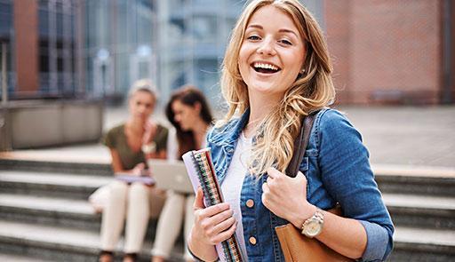 Ragazza con dei libri in mano sorride davanti all'obiettivo