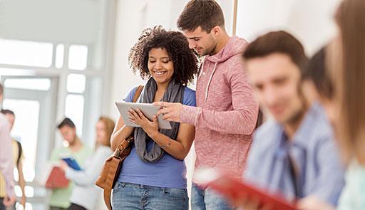 Ragazzo e ragazza che consultano un libro sorridendo
