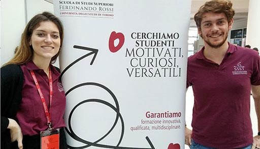 Ragazzo e ragazza accanto a uno stand della Scuola di Studi Superiore Ferdinando Rossi