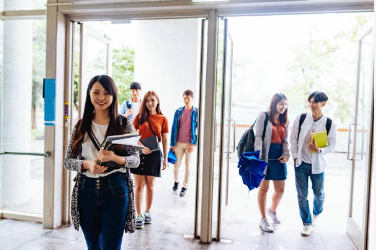 gruppo di studenti e studentesse che varcano una porta per andare a lezione