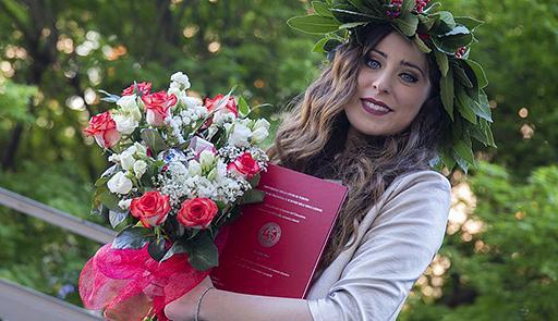 studentessa appena laureata con la tesi di laurea e un mazzo di fiori in mano
