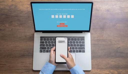 mani che impugnano uno smartphone davanti alla tastiera un pc