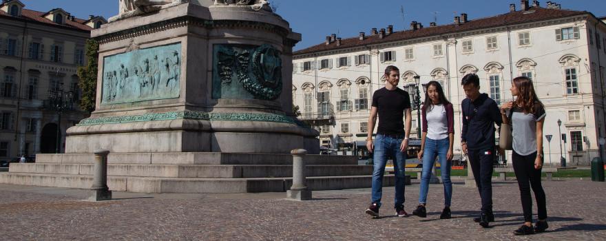 quattro studenti, italiani e stranieri, due ragazzi e due ragazze in una piazza di Torino